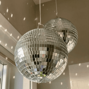 The hanging mirror ball surface is covered with tiny mirrored squares, which can reflect light on the room. Disco ball is a round object with a mirrored surface that reflects light in many directions, creating a complex display. The ball is usually pendent from the ceiling and rotates to cast reflected light on the surrounding surfaces. The surface of a disco ball is made up of hundreds or thousands of small, mirrored facets that are almost all the same size and shape. When light reflects off these mirrors, it scatters in many directions, producing a unique effect. The rotation of the mirror globe creates a profusion of moving spots.