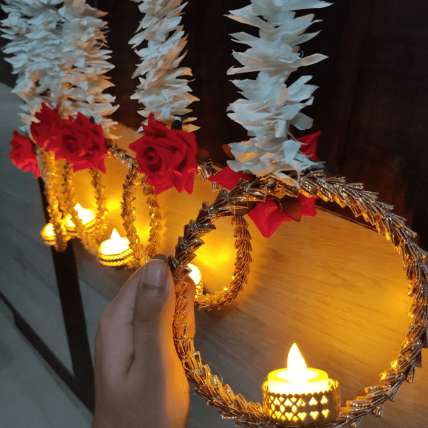 During Diwali, Torans are hung across doorways as a symbol of welcome and prosperity. These decorative pieces are usually made with vibrant marigold flowers, auspicious gajra leaves, and delicate rose and ring. Traditional Diwali decorations include lights, diyas (oil lamps made from clay), flowers (like these marigold garlands), torans (decorative door hangings), and rangoli, a type of intricate art crafted by flowers. One Box contains 5 Pieces of Elegant Artificial Flower String with LED Lamps /Diya. Product exactly as shown in Image. Length of White flowers is 3 Ft / 36 Inches . Total length of each string is approx 42 Inches. Attractive Roses attached on hanging are Red and made of Velvet. Ring Size below hanging is big and gives attractive look to wall / door decor.