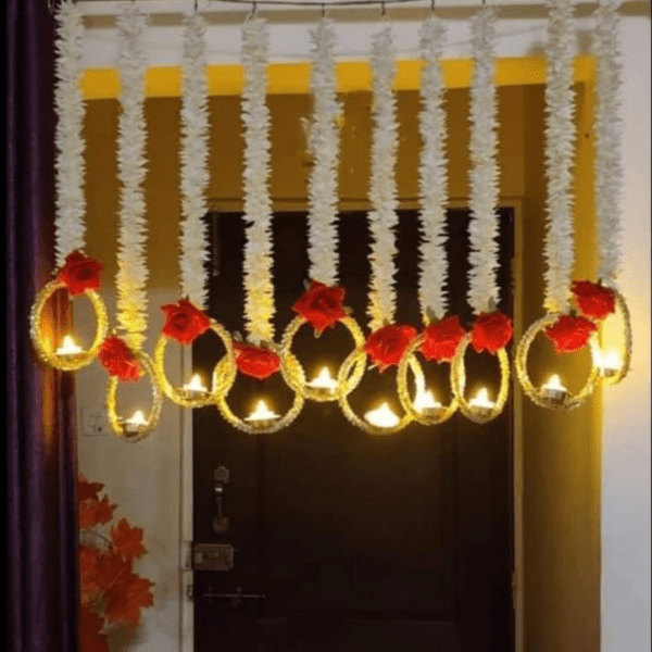 During Diwali, Torans are hung across doorways as a symbol of welcome and prosperity. These decorative pieces are usually made with vibrant marigold flowers, auspicious gajra leaves, and delicate rose and ring. Traditional Diwali decorations include lights, diyas (oil lamps made from clay), flowers (like these marigold garlands), torans (decorative door hangings), and rangoli, a type of intricate art crafted by flowers. One Box contains 5 Pieces of Elegant Artificial Flower String with LED Lamps /Diya. Product exactly as shown in Image. Length of White flowers is 3 Ft / 36 Inches . Total length of each string is approx 42 Inches. Attractive Roses attached on hanging are Red and made of Velvet. Ring Size below hanging is big and gives attractive look to wall / door decor.