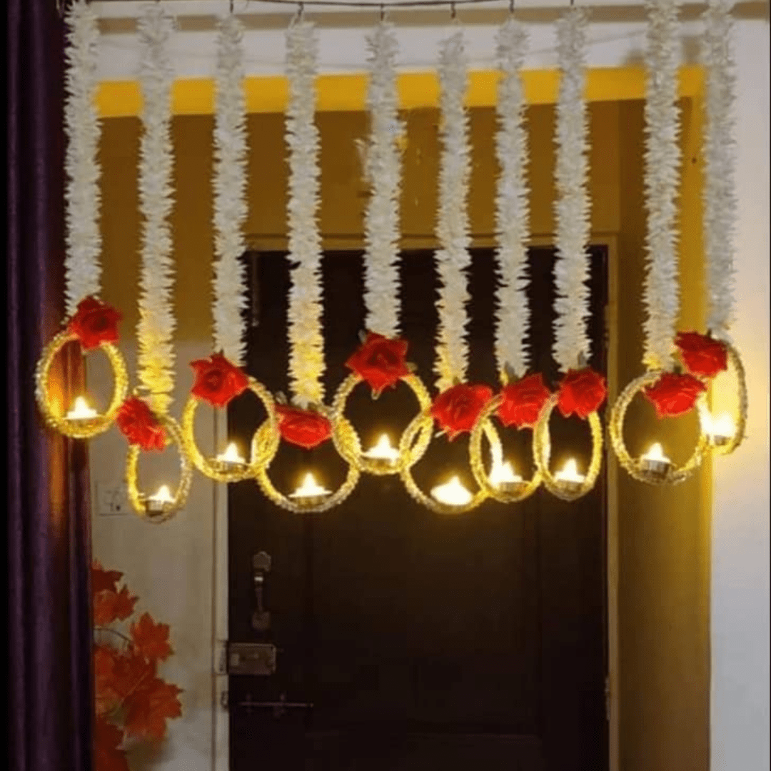 During Diwali, Torans are hung across doorways as a symbol of welcome and prosperity. These decorative pieces are usually made with vibrant marigold flowers, auspicious gajra leaves, and delicate rose and ring. Traditional Diwali decorations include lights, diyas (oil lamps made from clay), flowers (like these marigold garlands), torans (decorative door hangings), and rangoli, a type of intricate art crafted by flowers. One Box contains 5 Pieces of Elegant Artificial Flower String with LED Lamps /Diya. Product exactly as shown in Image. Length of White flowers is 3 Ft / 36 Inches . Total length of each string is approx 42 Inches. Attractive Roses attached on hanging are Red and made of Velvet. Ring Size below hanging is big and gives attractive look to wall / door decor.